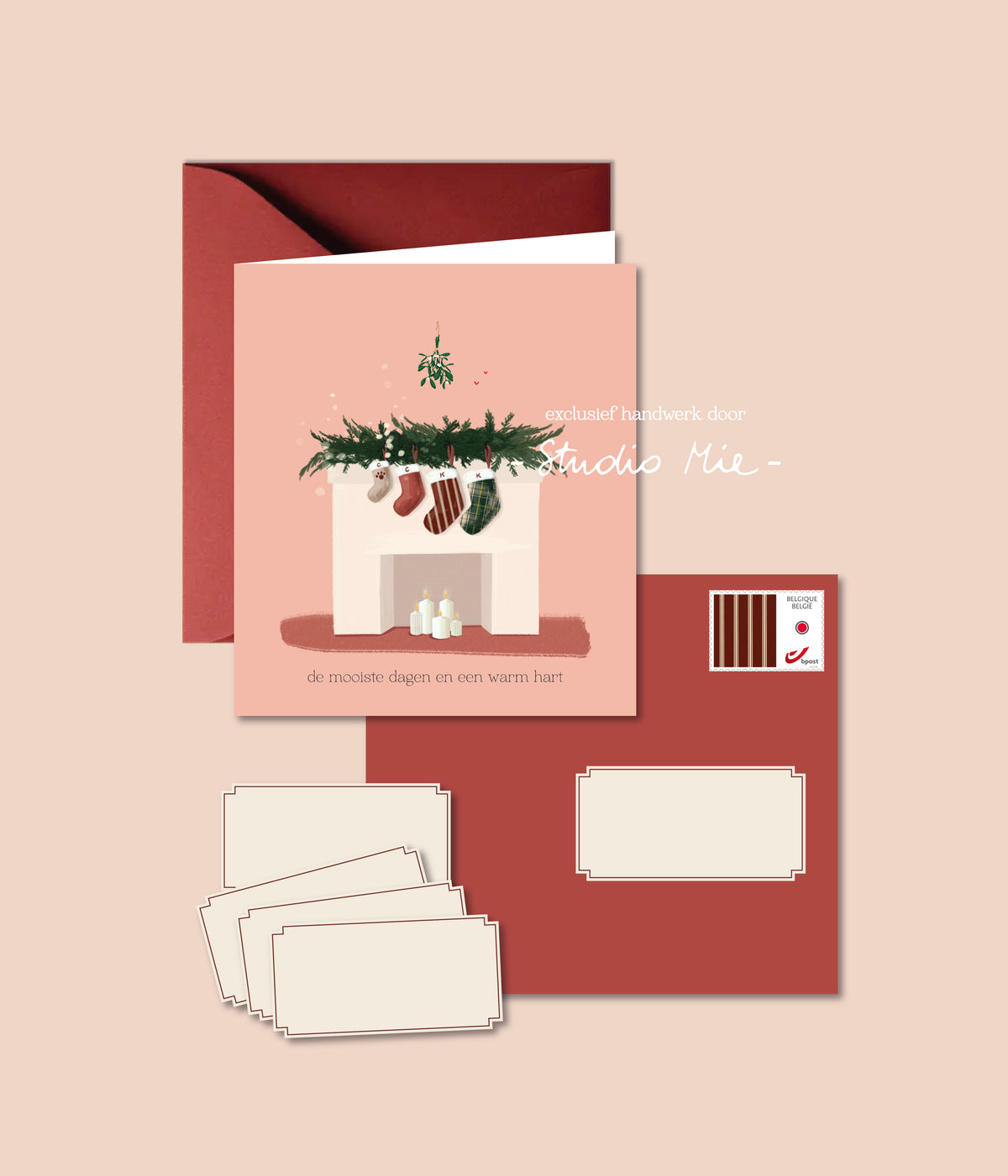 Roze familiekerstkaart met vier kerstsokken aan de schouw, met rode envelop, adresstickers en bijpassende postzegel