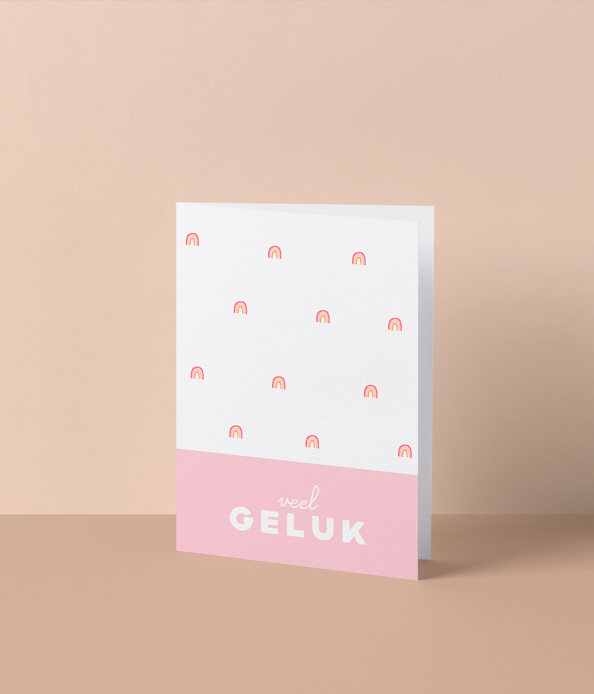 Wenskaart met kleine roze en oranje regenboogjes en de tekst ‘Veel geluk’ op een roze balk