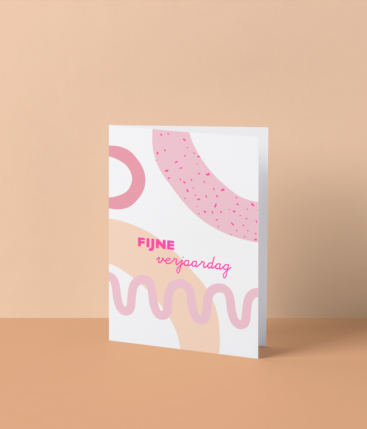 Witte wenskaart met grafische roze en perzikkleurige vormen en de tekst ‘Fijne verjaardag’ in fluo roze letters