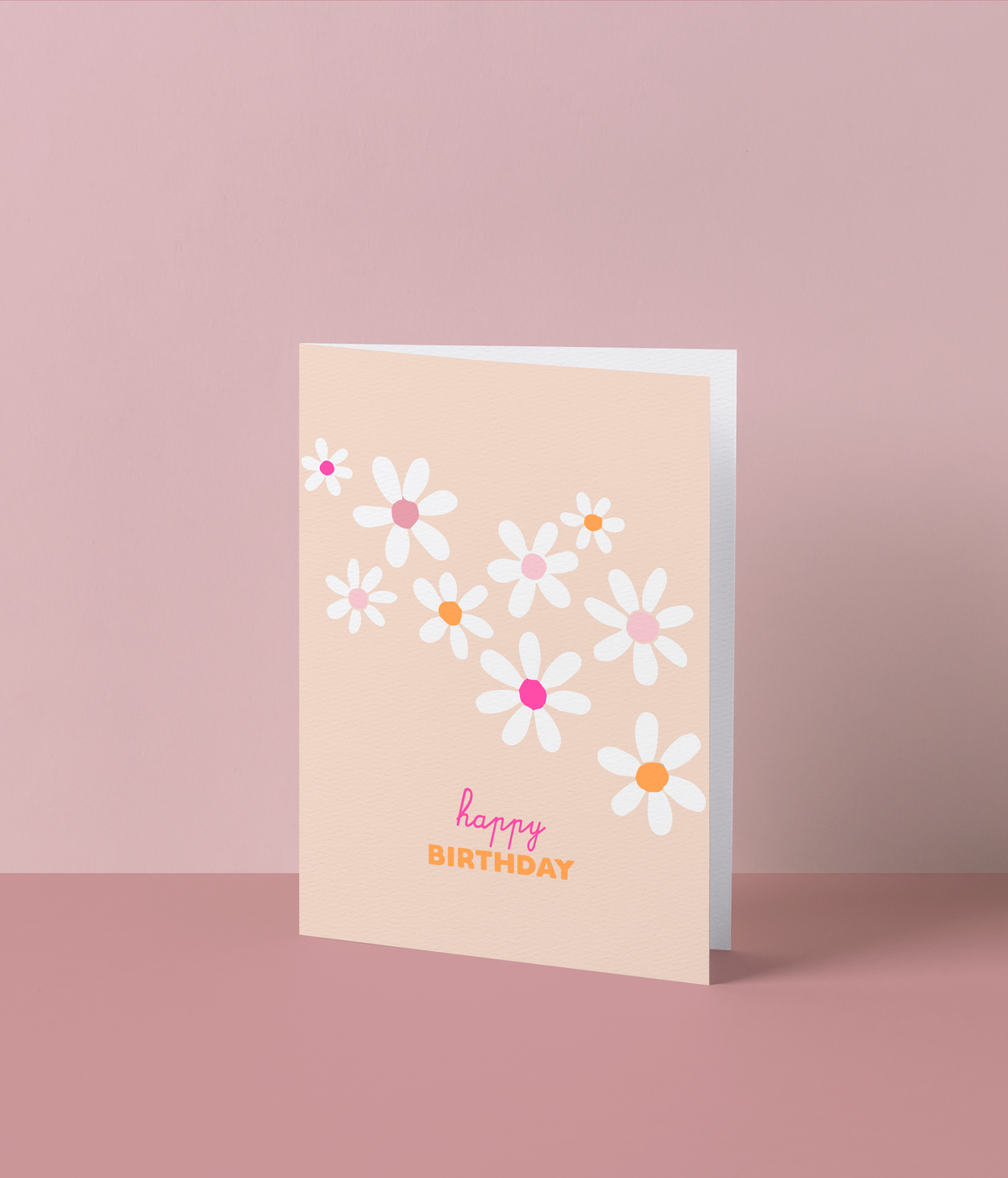 Perzikkleurige wenskaart met witte madeliefjes met roze en oranje hartjes en de tekst ‘Happy birthday’