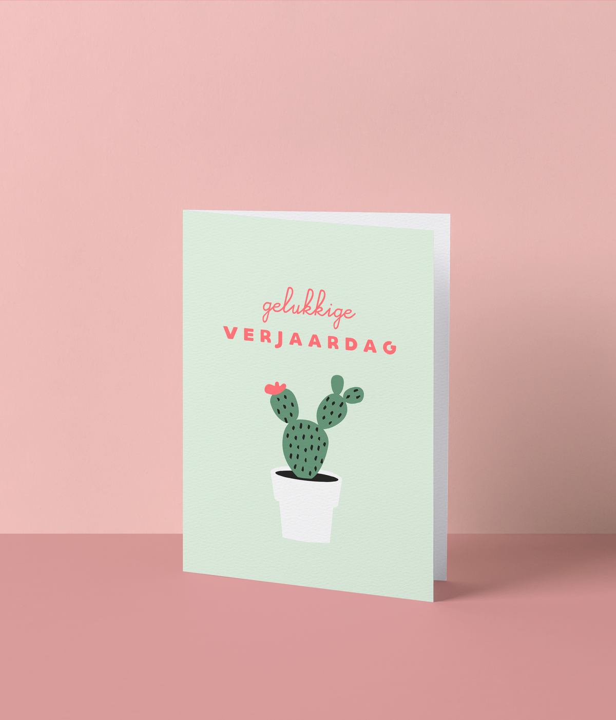 Muntgroene wenskaart met een cactus met een roze bloempje in een witte pot en de tekst ‘Gelukkige verjaardag’
